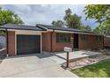 A brick single-Gathering home with a concrete driveway and small decorative rock bed at 6176 Ammons St, Arvada, CO 80004