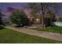 Charming brick home with a well-manicured lawn and mature tree at dusk at 805 S Everett St, Lakewood, CO 80226