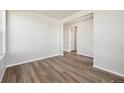 Clean, empty living room featuring hardwood floors and natural light streaming through a doorway and window at 2277 Serenidad St, Brighton, CO 80601