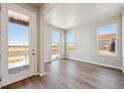 Bright living room with hardwood floors, natural light from large windows, and open access to front door at 2277 Serenidad St, Brighton, CO 80601