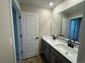 Bathroom featuring double sinks with black faucets, gray cabinetry and a large mirror at 18328 E 93Rd Pl, Commerce City, CO 80022