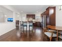 A view of the kitchen featuring dark cabinets, stainless appliances, granite island, breakfast bar and hardwood floors at 5480 Danube St, Denver, CO 80249
