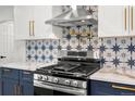 Modern kitchen featuring stainless steel appliances, stylish backsplash and custom white and blue cabinets at 3640 Forest St, Denver, CO 80207