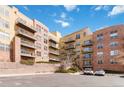 Exterior building view showcasing balconies, brick accents, parking, and landscaping against a partly cloudy blue sky at 9079 E Panorama Cir # 520, Englewood, CO 80112