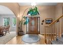 Elegant foyer featuring a wooden front door, hardwood floors, staircase, and arched doorway at 8007 Sunrise Cir, Frederick, CO 80516
