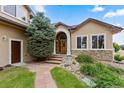 Charming home featuring a stone archway, brick steps, and a wooden door with green landscaping at 8007 Sunrise Cir, Frederick, CO 80516