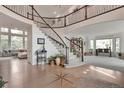 Expansive foyer features a hardwood floor with starburst design, winding staircase, and second-story balcony at 10773 Cougar Rdg, Lone Tree, CO 80124