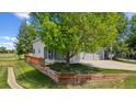 Charming two-story home with a wooden retaining wall and mature landscaping on a sunny day at 10570 Echo Ct, Firestone, CO 80504