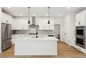 Modern kitchen with white cabinetry, stainless steel appliances, a center island, and hardwood floors at 42974 Colonial Trl, Elizabeth, CO 80107