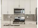 Modern kitchen features stainless steel appliances, stylish backsplash, and quartz countertops at 20982 E 66Th Ave, Aurora, CO 80019