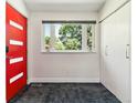 Bright entryway features a red door, closet, plush carpet and a window view of lush greenery at 5480 W Iowa Ave, Lakewood, CO 80232
