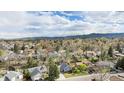 Expansive aerial view of a neighborhood with mature trees and mountain views in the distance at 7746 W Quarto Dr, Littleton, CO 80128