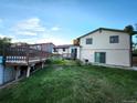 Spacious backyard featuring a well-kept lawn and two-story home with wooden deck, flower garden, and sliding glass door at 3216 S Granby Way, Aurora, CO 80014
