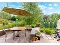 A cozy backyard patio with a dining table, umbrella, and lush greenery, perfect for outdoor entertaining and relaxation at 1902 Pioneer Cir, Lafayette, CO 80026