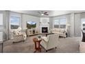 Cozy living room with a fireplace, neutral tones, and lots of natural light through large windows at 2080 Shadow Creek Dr, Castle Rock, CO 80104