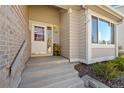 Inviting front entrance with a white door, brick accents, and manicured landscaping at 5434 S Ward Way, Littleton, CO 80127