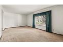 Spacious living room featuring neutral carpet, large window, and ample natural light at 9004 E Floyd Ave, Denver, CO 80231