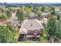 Back of brick home featuring a wooden deck with outdoor seating surrounded by mature trees at 1 Silver Fox Dr, Greenwood Village, CO 80121