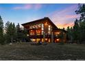 Two-story rustic modern home with balconies, a fire pit, and large windows overlooking a wooded lot at 5976 Stone Creek Dr, Evergreen, CO 80439