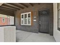 Covered front porch with dark painted brick, a modern light fixture, and concrete flooring at 1455 Hudson St, Denver, CO 80220