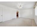 Bright living room with a ceiling fan, white walls and tiled flooring, leading into the kitchen at 200 Perry St, Denver, CO 80219