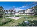 View of a home's backyard with a pergola on a well-maintained lawn under a blue sky at 2781 Savage Rd, Elizabeth, CO 80107