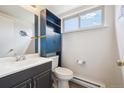 Bathroom with a blue cabinet, sink, toilet, and a window that allows for natural light to filter in at 3660 S Ouray Cir, Aurora, CO 80013