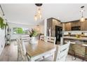 Bright dining room with a wooden table, hanging lights, and kitchen view at 6678 S Arapahoe Dr, Littleton, CO 80120