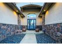 Inviting front entrance with stone accents, a decorative door, and manicured landscaping at 1743 Homestead Dr, Fort Lupton, CO 80621