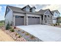 Stylish gray home showcasing a large driveway, two-car garage, and beautiful landscaping at 3991 Descent St, Castle Rock, CO 80108