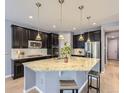 Modern kitchen features dark cabinetry, stainless steel appliances, and a large island with granite countertop at 10045 Copenhagen St, Parker, CO 80134
