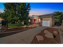 Brick home with a well-manicured lawn, featuring a pink door, covered porch, and a one car garage at 3241 Sheridan Blvd, Wheat Ridge, CO 80212