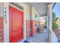 Red front door and cozy porch furniture with wicker chairs at 14653 E Crestridge Dr, Centennial, CO 80015