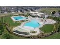 Aerial view of community pool area featuring multiple pools, seating, and playground at 148 Baler Ct, Brighton, CO 80601