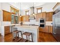 Spacious kitchen featuring custom wood cabinets, a central island with seating, and stainless steel appliances at 6194 Falcon Ridge Way, Morrison, CO 80465