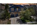 Two-story home with stone accents, blue siding, a two-car garage, and solar panels on the roof against a colorful sky at 25245 E Park Crescent Dr, Aurora, CO 80016