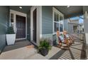 Inviting covered porch featuring rocking chairs with stylish pillows, plants, and a welcoming front door at 12826 Lake Port St, Longmont, CO 80504