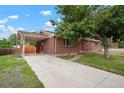 The brick house has a long driveway leading to a covered parking area, and the lawn needs some TLC at 6698 S Wellington Ct, Centennial, CO 80121