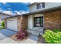 Inviting front entrance with brick accents, complemented by landscaping and a convenient two-car garage at 302 Northridge Rd, Highlands Ranch, CO 80126