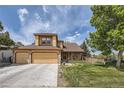 Charming two-story home boasts a three car garage and a well-manicured lawn, set against a beautiful blue sky at 9001 W Chatfield Dr, Littleton, CO 80128