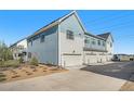 Rear exterior of a townhome with three garages and a convenient driveway, surrounded by landscaping at 7889 Yampa River Ave, Littleton, CO 80125