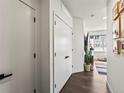 Clean, modern hallway with hardwood floors, white doors, and artwork leading to the living space at 1898 S Bannock St # 404, Denver, CO 80223