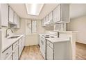 Bright kitchen featuring white cabinets and appliances, complemented by a modern countertop and ample natural light at 17053 E Tennessee Dr # 101, Aurora, CO 80017