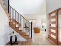 Inviting foyer with hardwood floors, staircase with black railings, and modern front door at 1 Winged Foot Way, Littleton, CO 80123