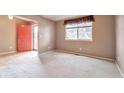 Bright living room with a large window, neutral carpet, light walls, and a coral front door at 6731 E 128Th Pl, Thornton, CO 80602