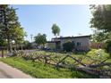 Street view of the home with wood fence and xeriscape landscaping features at 1075 S Ames St, Lakewood, CO 80226