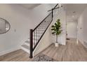 Bright and airy staircase with dark wood railing, light wood floors, and decorative potted plant at 520 Columbine St, Denver, CO 80206