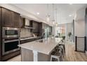 Open kitchen with stainless steel appliances, center island with seating, and stylish pendant lighting at 9072 E 47Th Ave, Denver, CO 80238