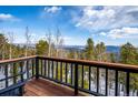 Breathtaking mountain view from a wooden deck with black railing and trees at 10756 Timothys Dr, Conifer, CO 80433