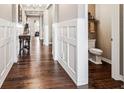 Inviting hallway with wood floors, wainscoting details and a view of the half bathroom at 8651 S De Gaulle Ct, Aurora, CO 80016